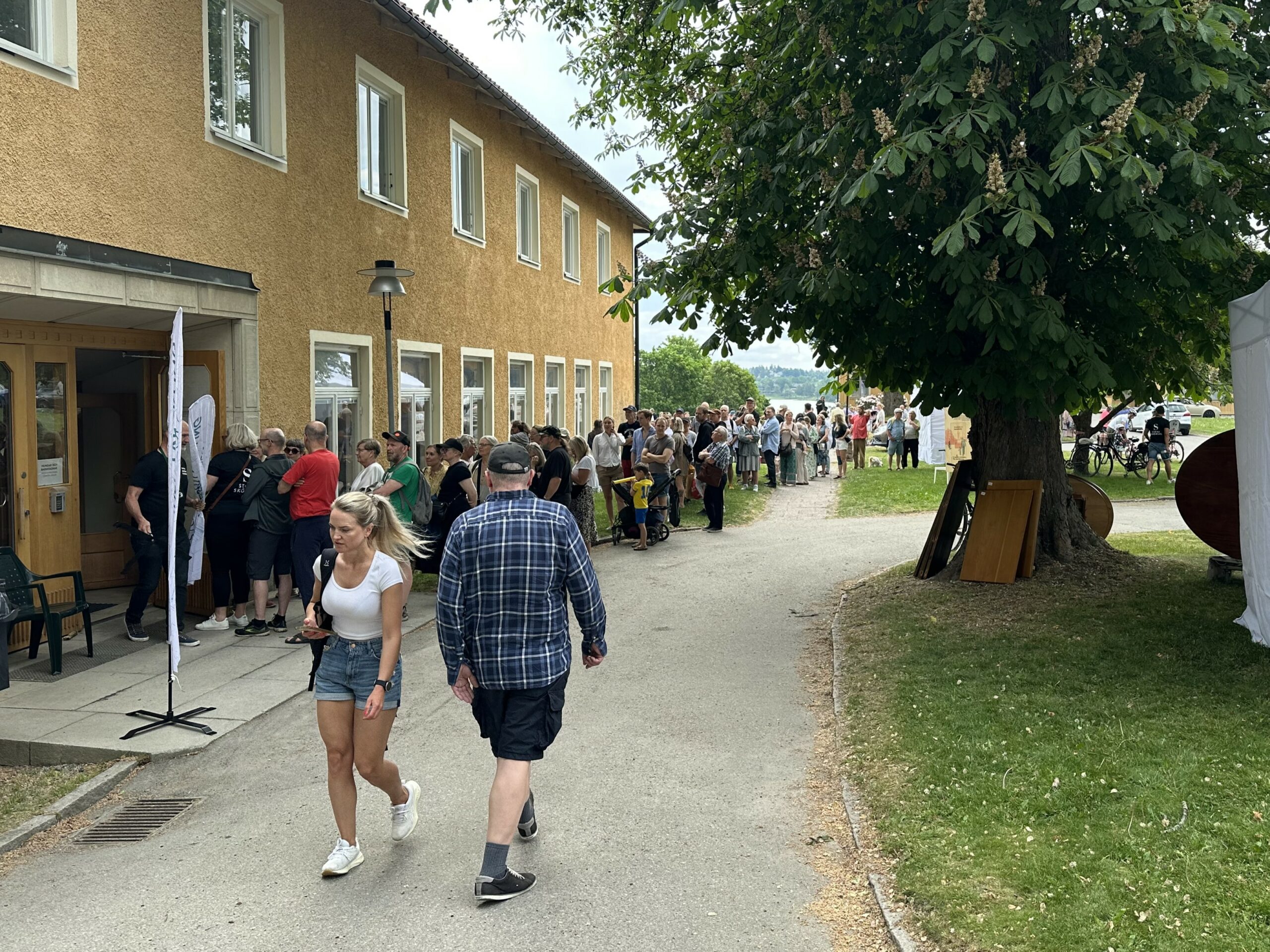 Människor i kö framför gult hus.
