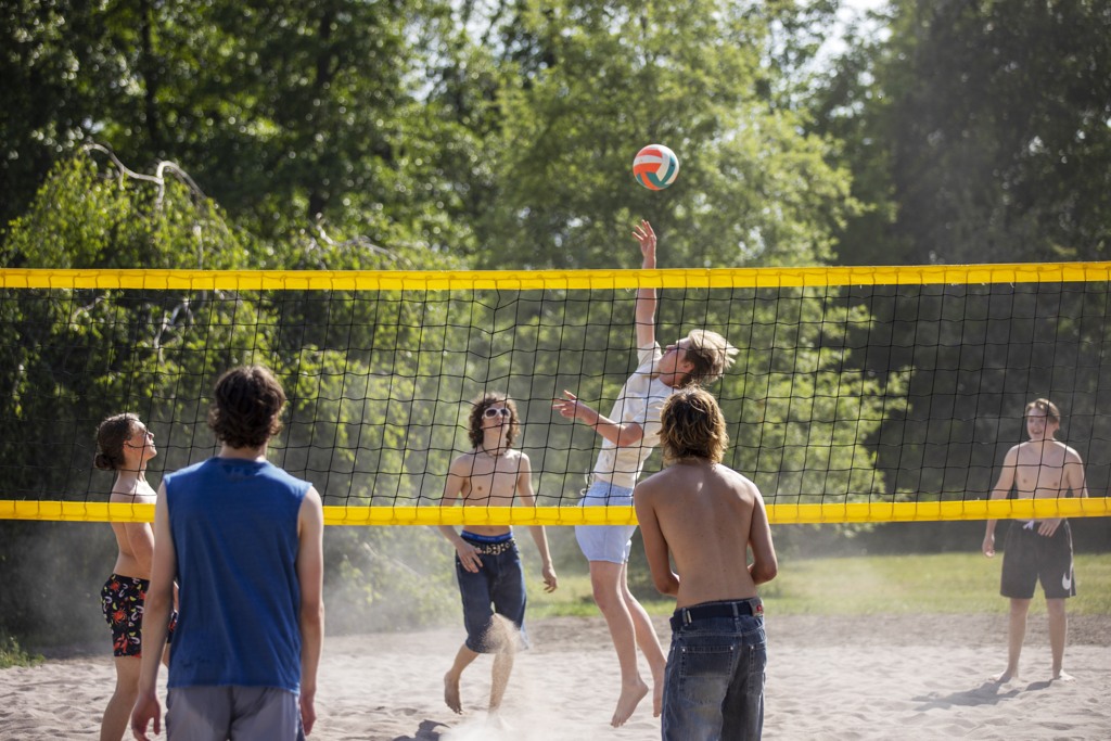 En grupp killar spelar beachvolleyboll en varm sommardag.