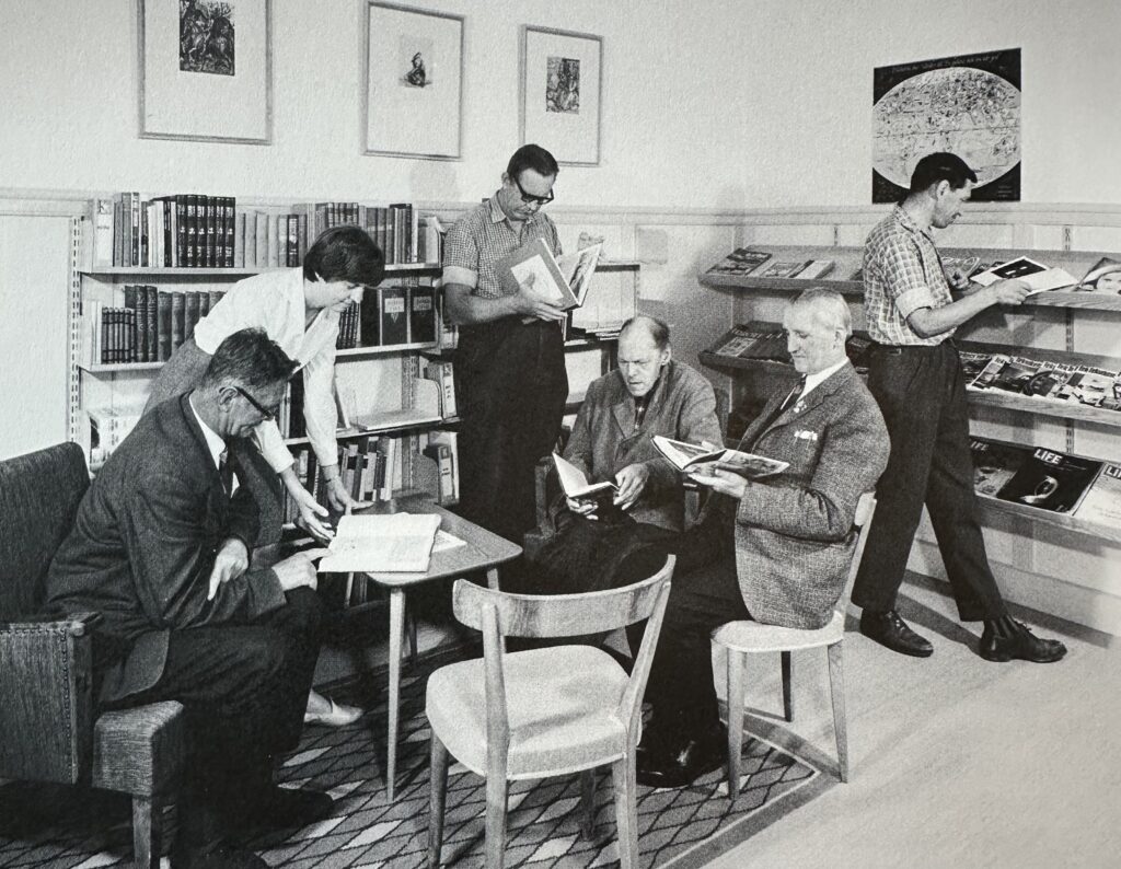 Svartvit bild på människor och tittar i böcker på bibliotek. Bilden troligen från tidigt 60-tal.