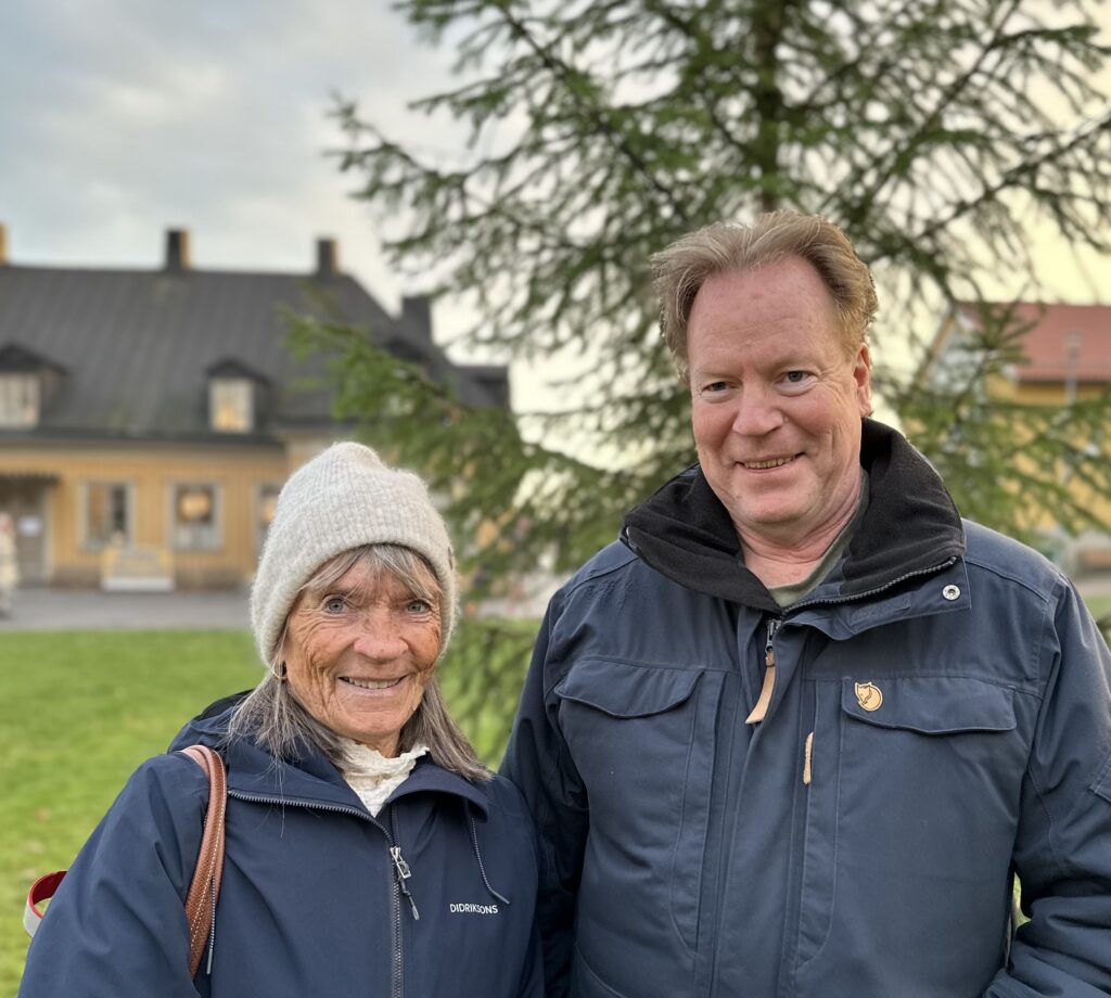 Kvinna och man i vinterkläder framför julgran och Kristinahuset. 